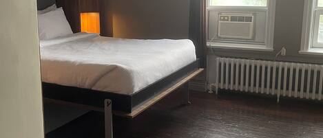 A bedroom with a bed, a radiator, and a window.