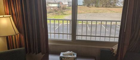 A hotel room with a large window, a table with a tissue box, and two chairs.