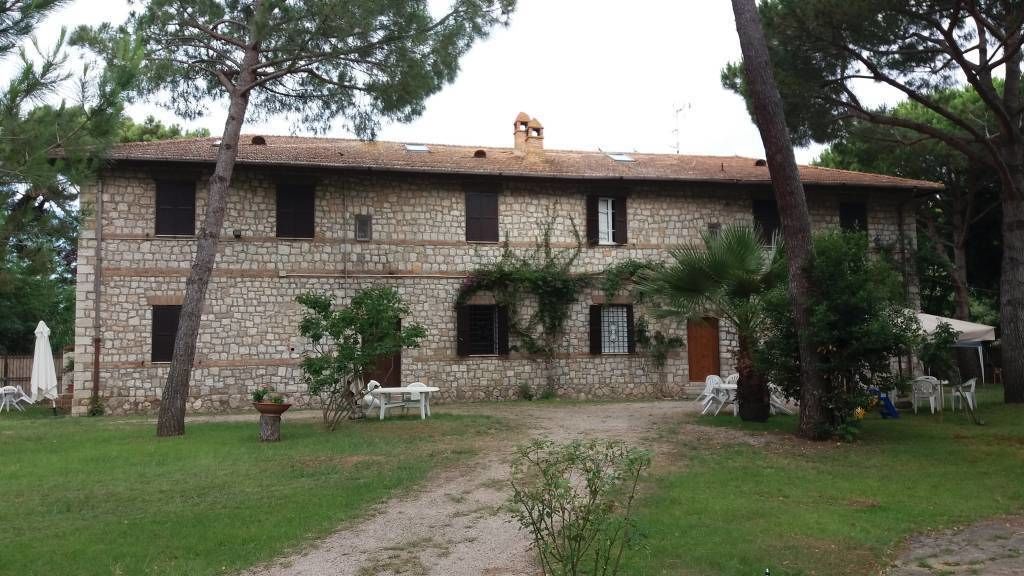A stone building with a tiled roof, a gravel path, and outdoor seating.