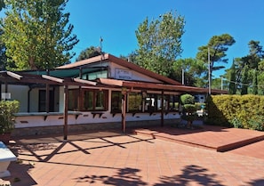 A reception area with a sign, a covered outdoor seating area, and a paved walkway. - Settebello Village (Fondi)