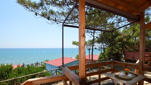A wooden deck with a view of the sea, a gazebo structure, and a table with a vase of flowers. - Settebello Village (Fondi)