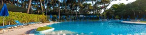 A swimming pool with lounge chairs and umbrellas, surrounded by trees. - Settebello Village (Fondi)
