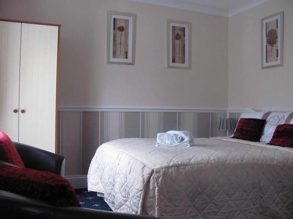 A hotel room with a bed, a chair, and a wardrobe.