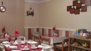 Comedor con mesas dispuestas para cuatro, sillas, un reloj de pared y un adorno decorativo.