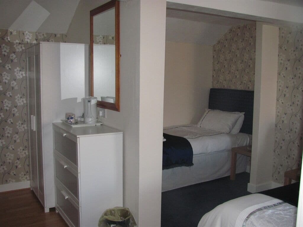 Ein Schlafzimmer mit Bett, Kommode und Spiegel.