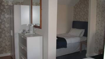 Ein Schlafzimmer mit Bett, Kommode und Spiegel.