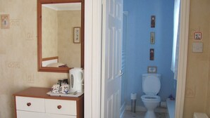 Un dormitorio con cómoda de madera, un espejo y vistas al baño.