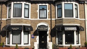 Un edificio en esquina con dos toldos negros que dicen 'Branston Lodge Guest House' y una puerta con un letrero que dice 'Bienvenido a Branston Lodge'.
