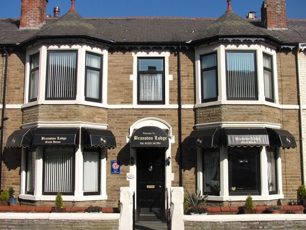 A corner building with two black awnings labeled "Branston Lodge Guest House" and a door with a sign reading "Welcome to Branston Lodge." - Branston Lodge (Blackpool)