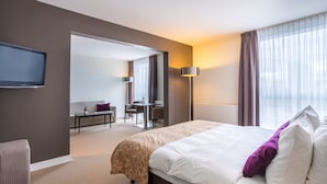 A hotel room with a large bed, a desk, and a television mounted on the wall. - The Rilano Hotel Munich, Trademark Collection by Wyndham (Munich)