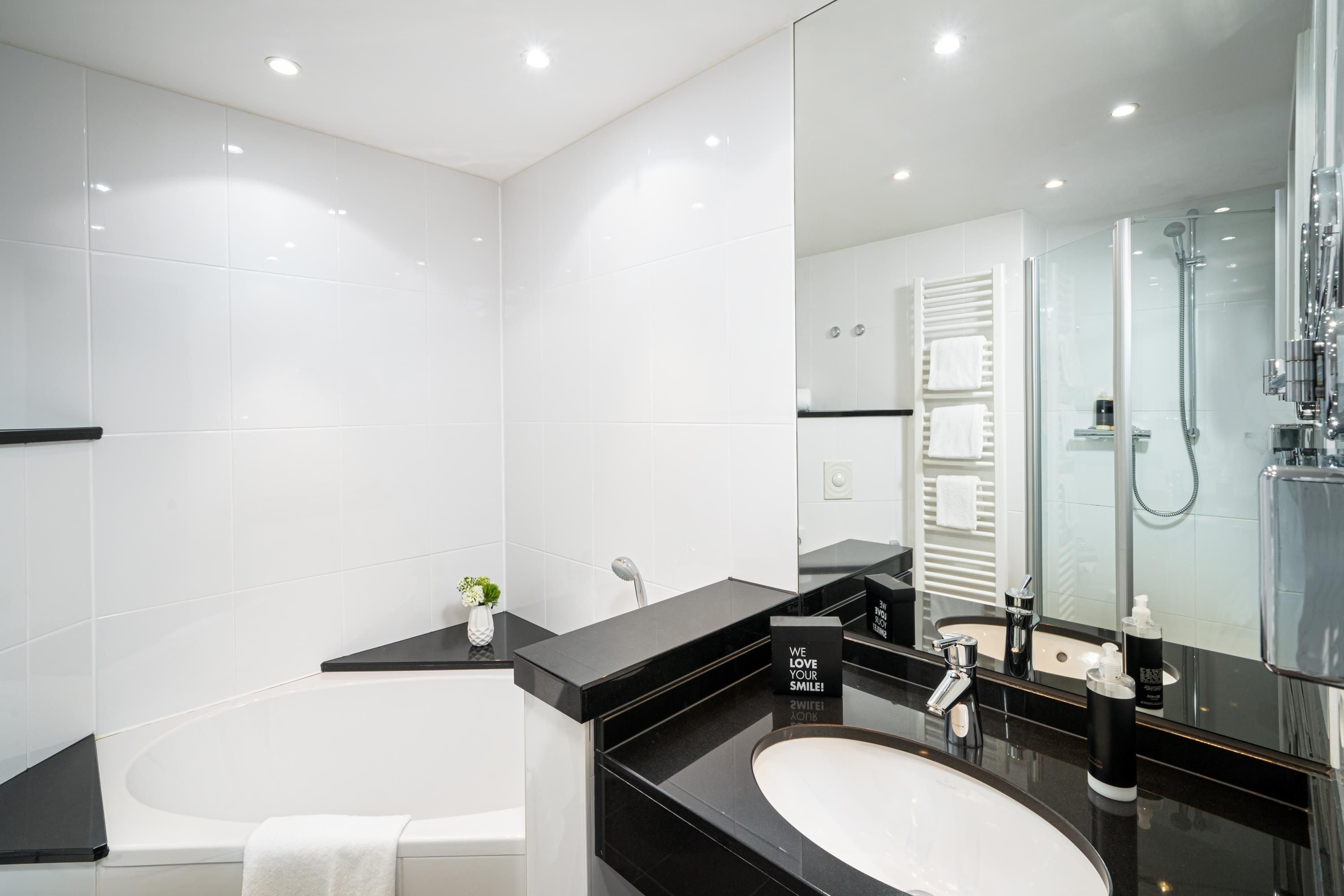 Un baño moderno con bañera, lavamanos y cabina de ducha con mampara de vidrio.