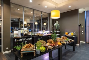 A breakfast buffet with a variety of breads, fruits, and beverages.