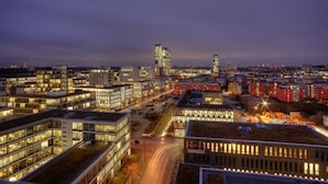 A cityscape at dusk with modern buildings and illuminated windows. - The Rilano Hotel Munich, Trademark Collection by Wyndham (Munich)
