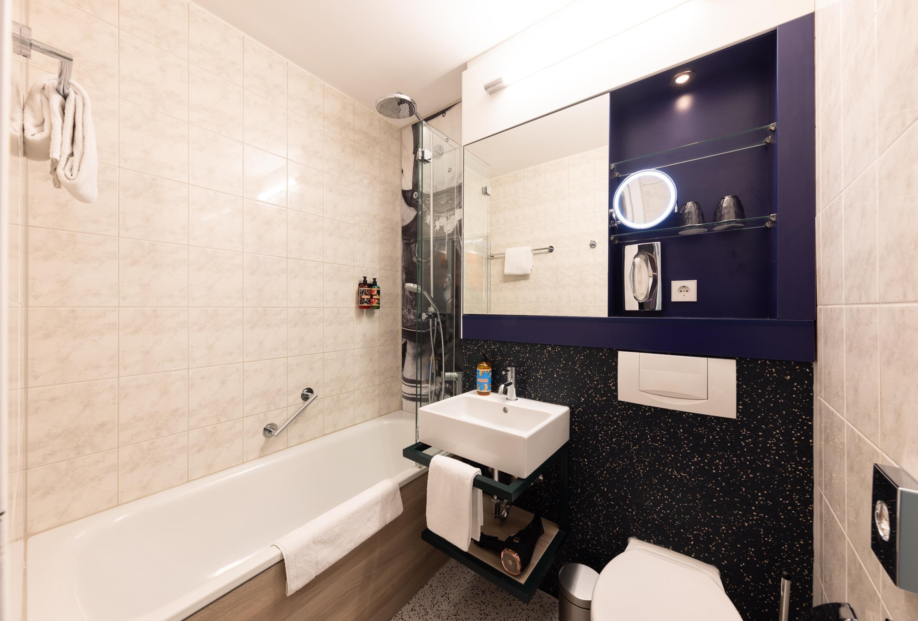 A modern bathroom with a bathtub, a shower, a sink, and a toilet.