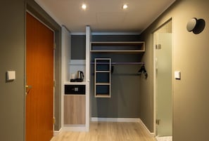 A compact room with a wooden door, built-in shelving, a small kitchen area, and a shower. - The Rilano Hotel Munich, Trademark Collection by Wyndham (Munich)
