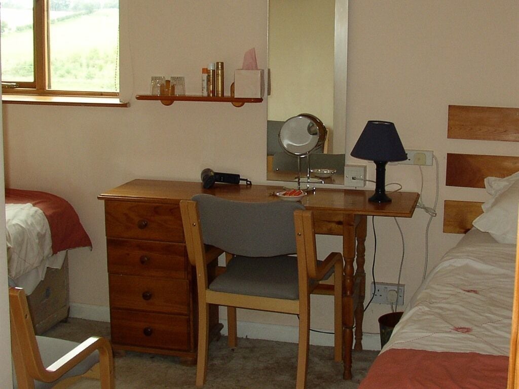 Ein Schlafzimmer mit einem Holztisch, einem Stuhl und einem Bett mit Kopfteil.