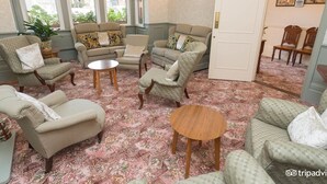 Un salón acogedor con una alfombra estampada, un conjunto de sofá, sillones y una mesita redonda.