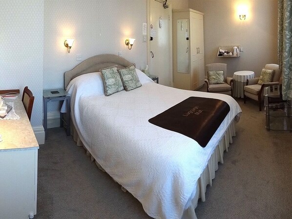 A hotel room with a large bed, bedside tables, a desk, and a chair.