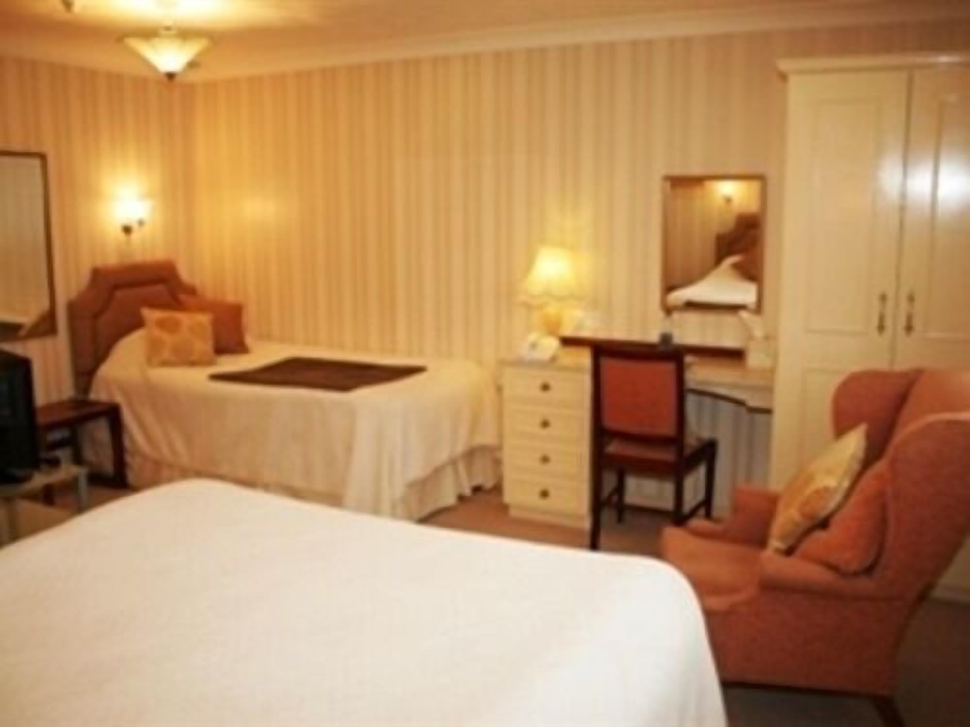A hotel room with a bed, a desk, a chair, a wardrobe, and a television.