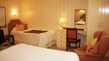 A hotel room with a bed, a desk, a chair, a wardrobe, and a television.