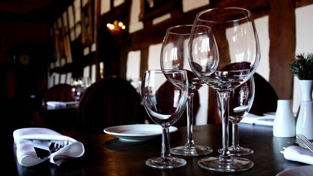 Taula preparada amb copes de vi i plats, indicant una zona de menjador a un restaurant.