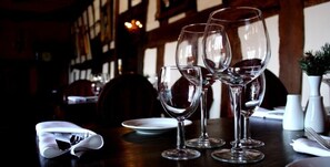 Mesa dispuesta con copas de vino y platos, indicando una zona de comedor en un restaurante.