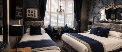 A hotel room with two beds, a chandelier, a large mirror, and a window with curtains.