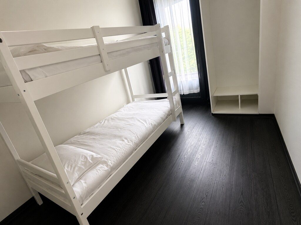 A bunk bed in a room with a dark wooden floor and white walls.