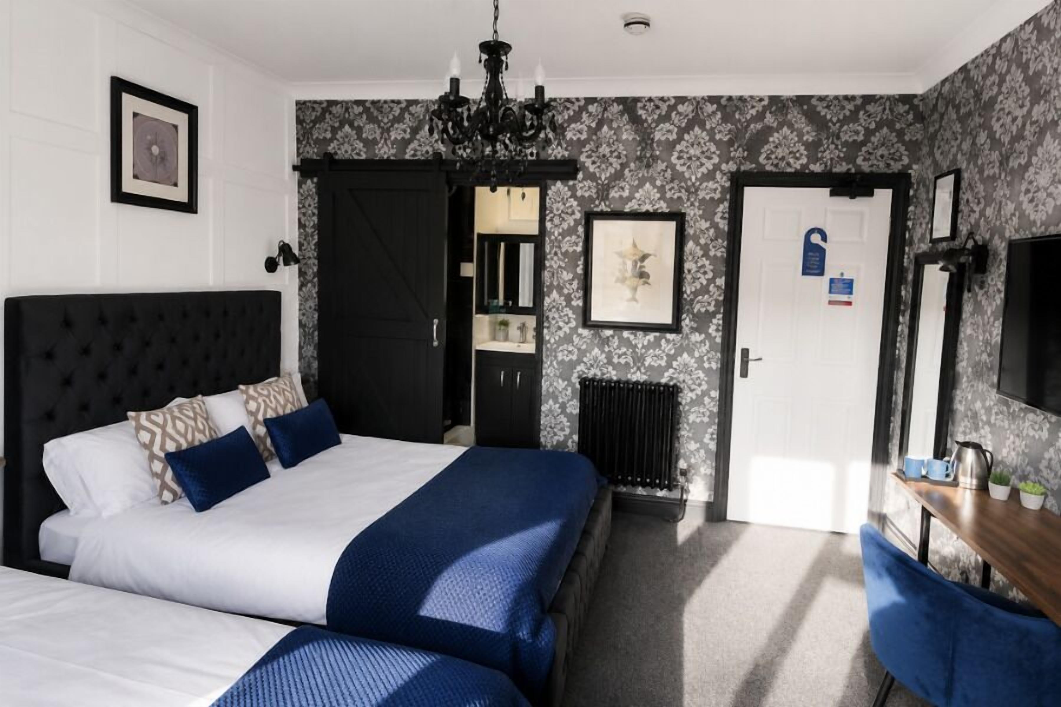 Habitación de hotel con una cama grande, un escritorio con una silla, un radiador y una puerta con un letrero.
