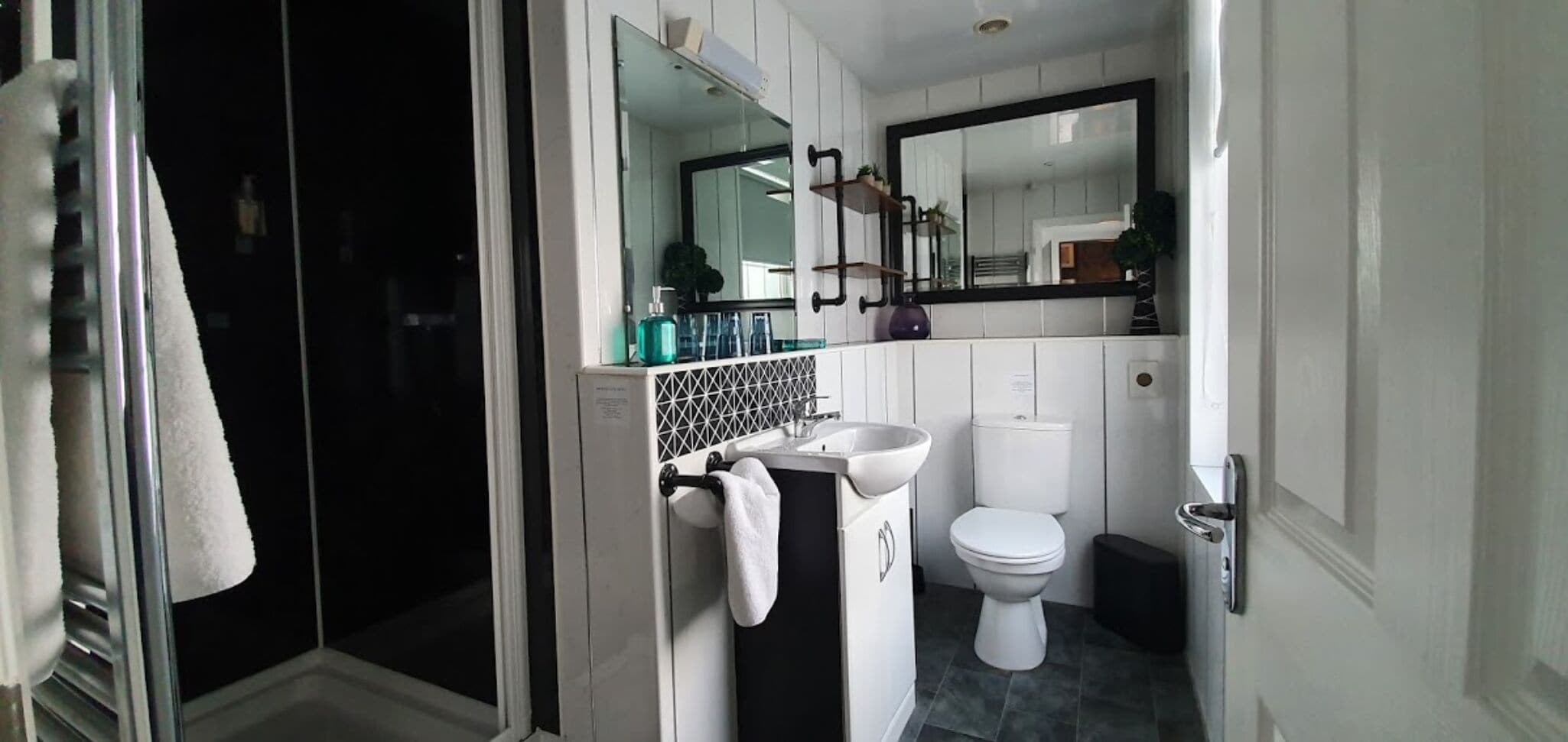 Un baño moderno con cabina de ducha de vidrio, un lavamanos blanco y un inodoro.