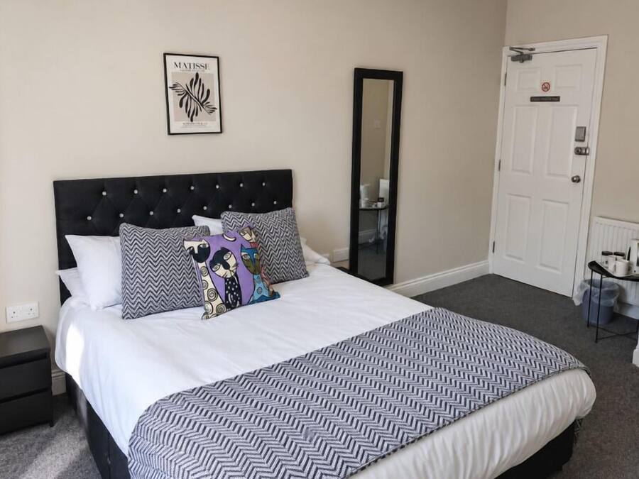 A neatly made bed with patterned bedding, a black headboard, and a framed artwork on the wall.