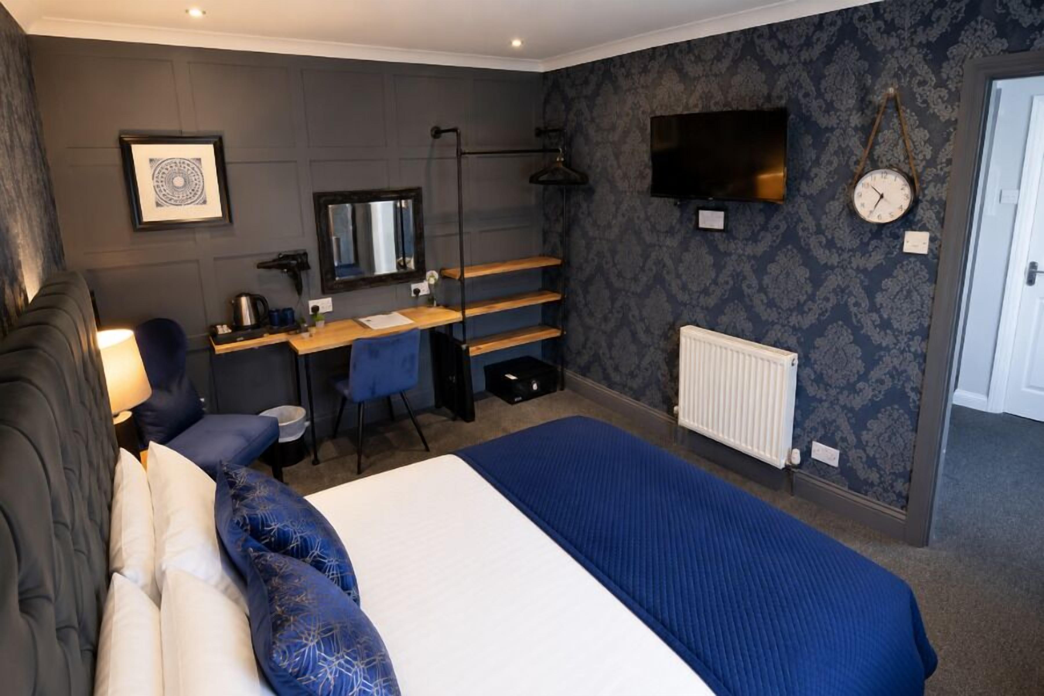 A bedroom with a bed, desk, chair, and a television on the wall.