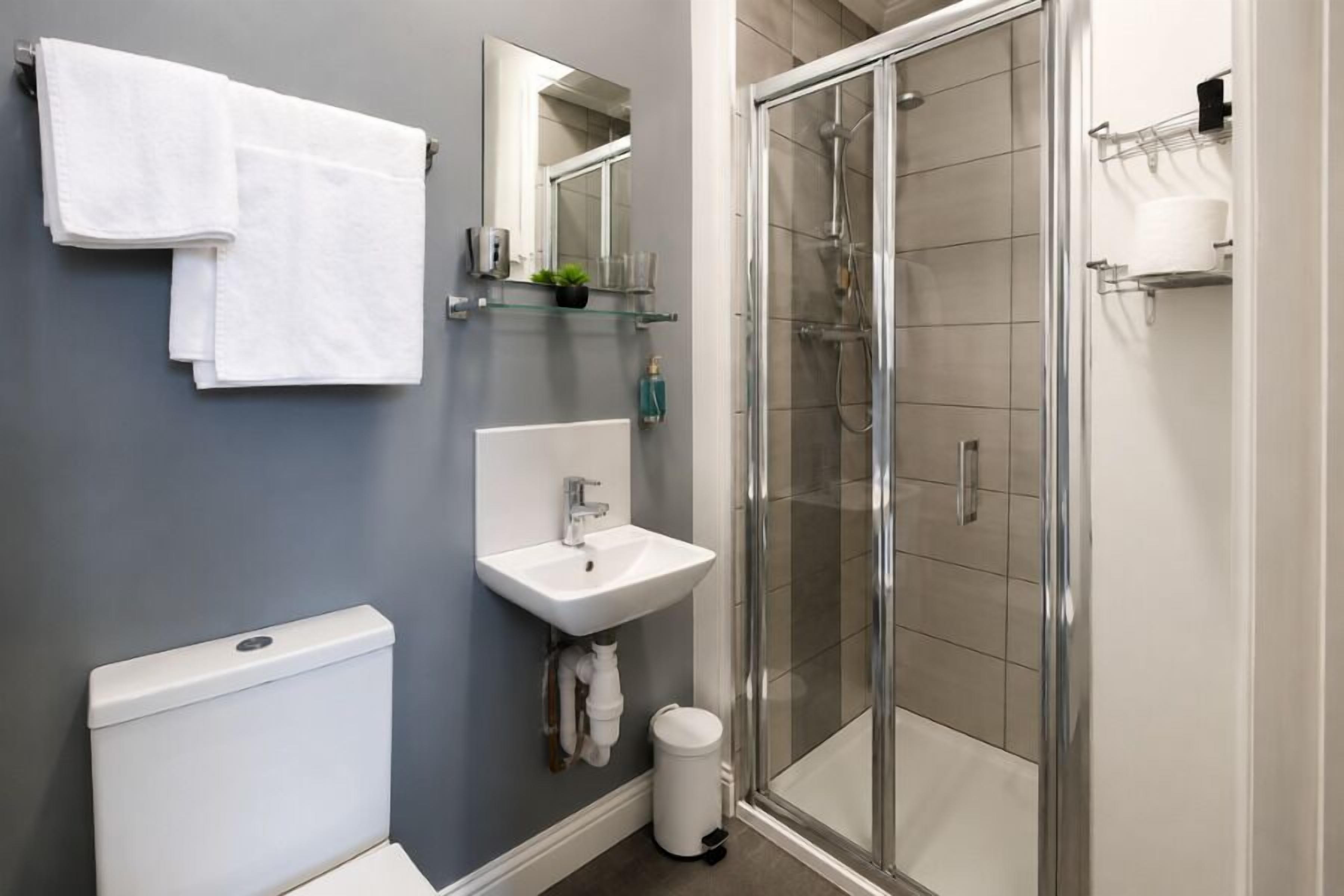 A modern bathroom with a toilet, sink, and glass shower enclosure.