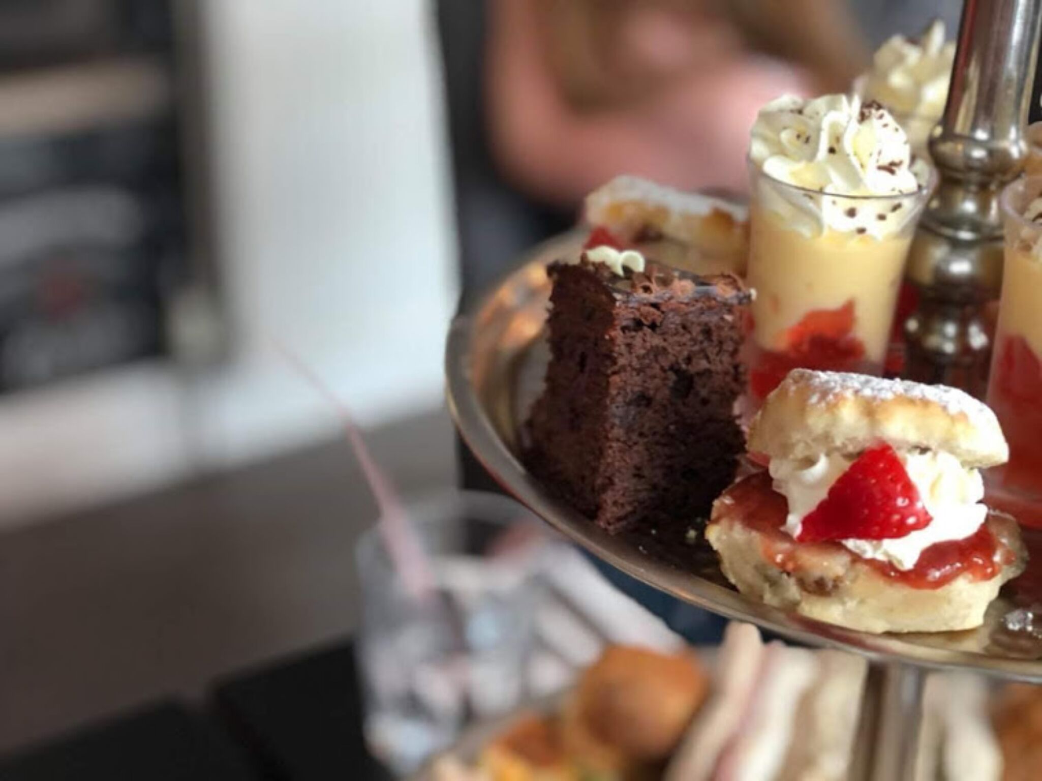 Una bandeja de postres con diversas golosinas, incluyendo una rebanada de pastel, un helado con crema batida y fresas, y un postre en vaso.