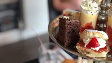 Una bandeja de postres con diversas golosinas, incluyendo una rebanada de pastel, un helado con crema batida y fresas, y un postre en vaso.