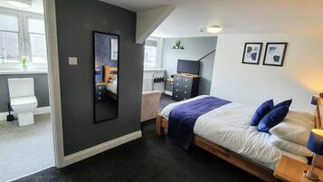 Un dormitorio moderno con una cama, mesita de noche y televisor.