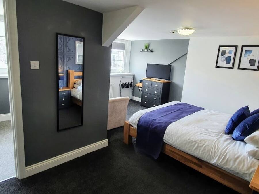 Un dormitorio moderno con una cama, mesita de noche y televisor.