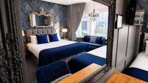 Ein Hotelzimmer mit einem großen Spiegel, einem Bett mit blauer Bettwäsche, einer Couch mit blauen Kissen und einem Holztisch.