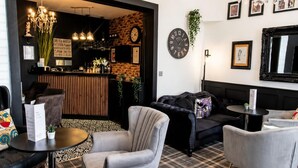 Ein moderner Lounge-Bereich mit Bar, Sitzgelegenheiten und Dekoelementen wie einer Uhr und gerahmten Bildern.