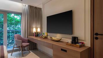 Habitación de hotel moderna con un ventanal grande, un escritorio con una computadora portátil, una silla, un televisor de pantalla plana y una cafetera.