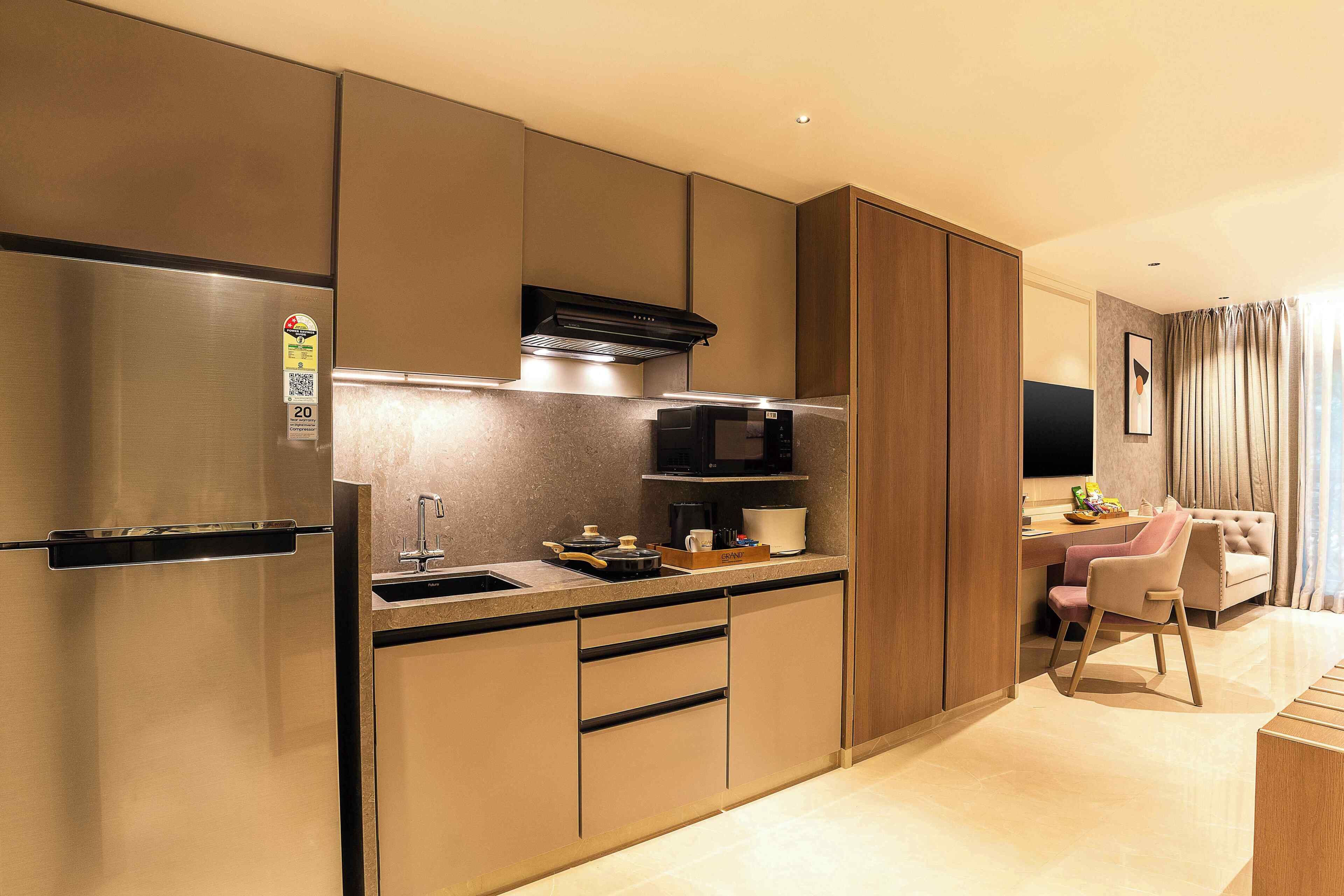 A modern kitchen with a built-in microwave, a refrigerator, and a dining area with a chair and table.