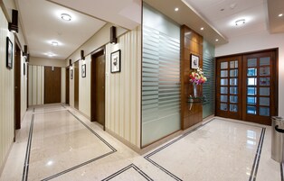 A hotel corridor with a polished marble floor, wooden doors, and framed pictures on the walls.