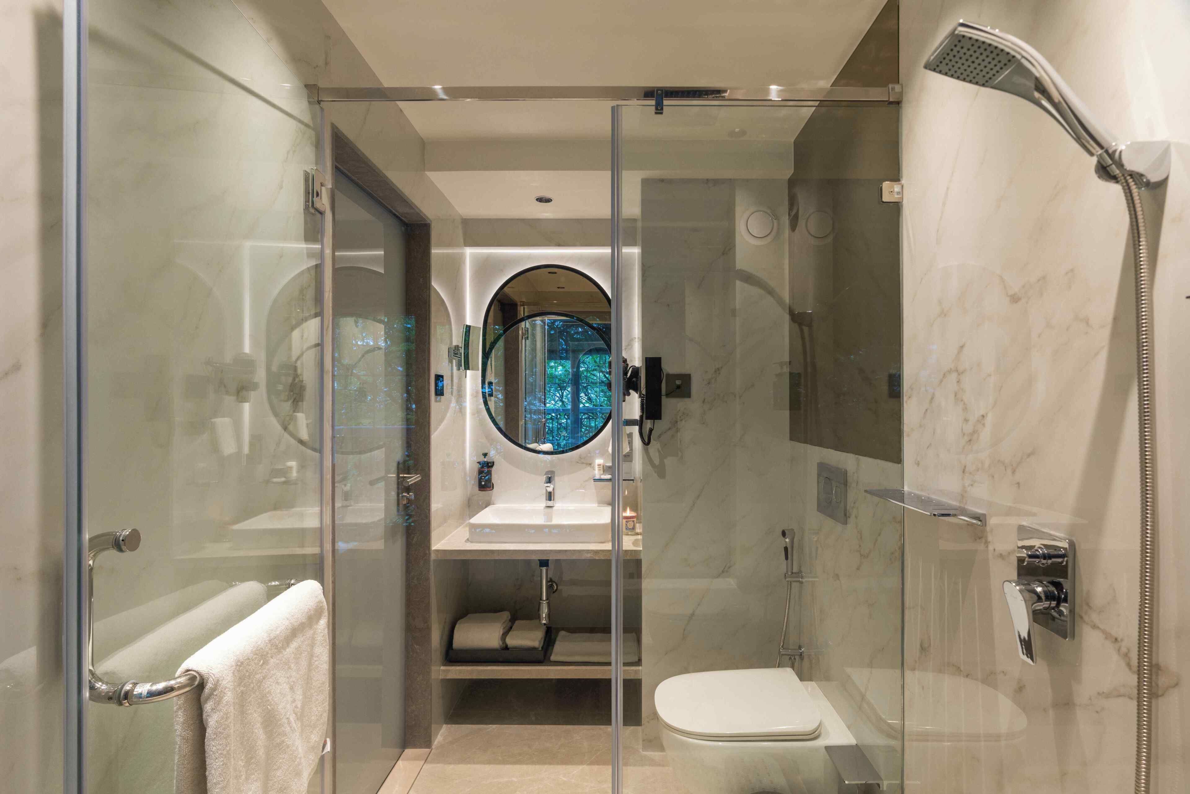 A modern bathroom with a glass-enclosed shower, a toilet, and a sink with a mirror.