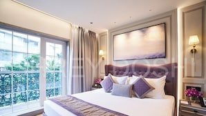 A hotel room with a large bed, a view through a window, and a painting on the wall.