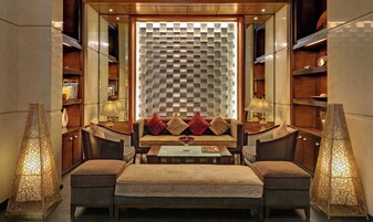 A cozy seating area with a sofa and ottomans, a small table, and two lamps.