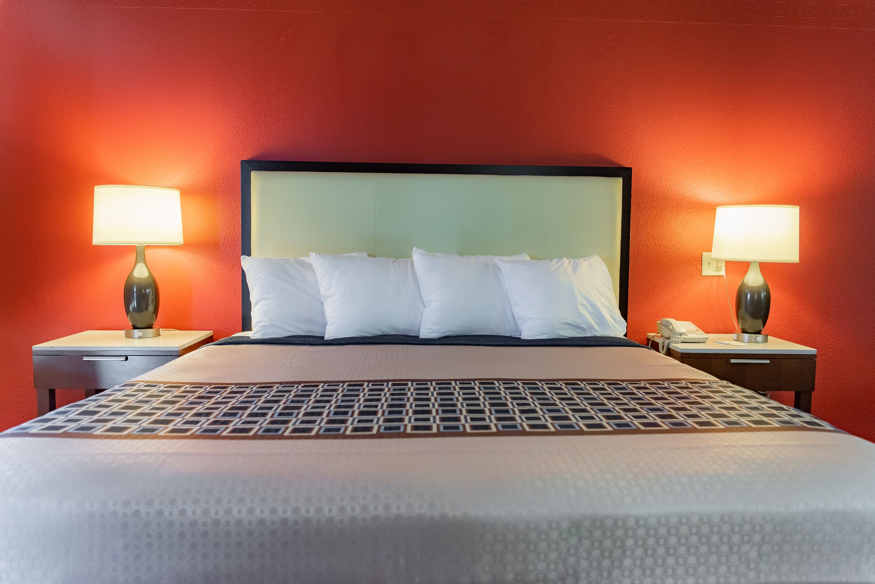 A hotel room with a bed, two bedside tables, and two lamps.