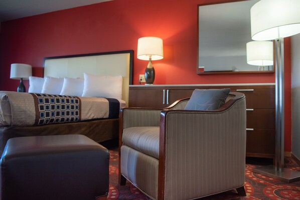 A hotel room with a bed, a chair, a desk, and a lamp. - Spencer Inn and Suites (Spencer)