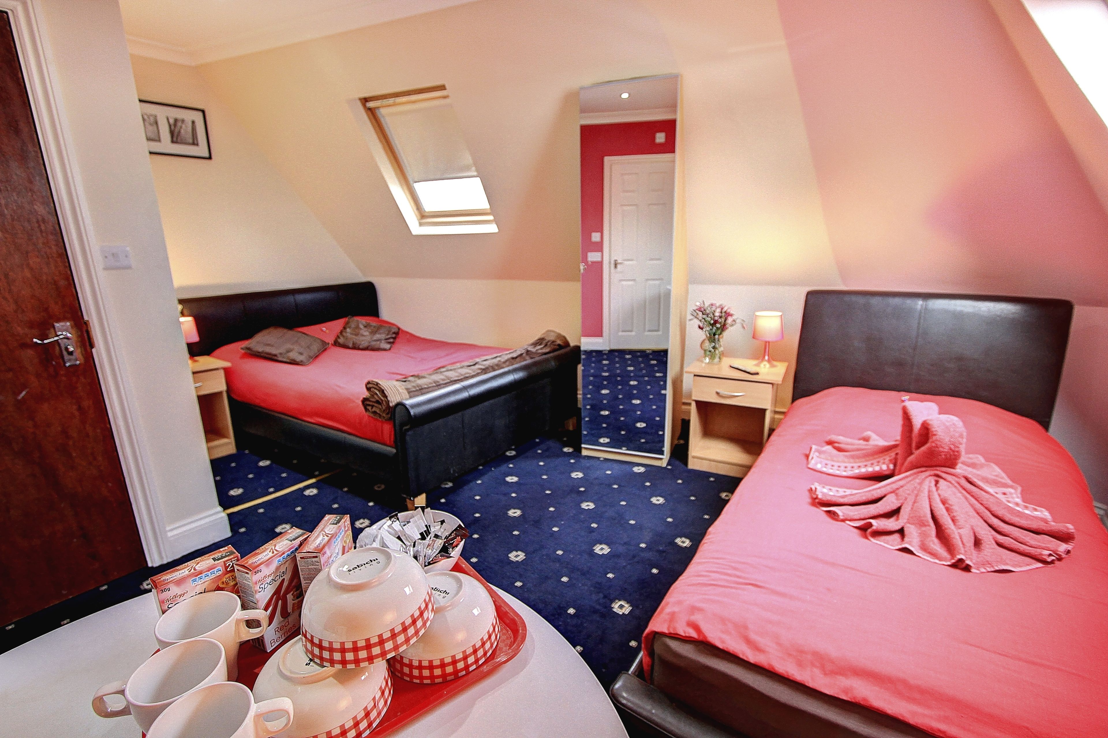 Une chambre d’hôtel avec deux lits, une table à manger avec des aliments pour le petit-déjeuner, un miroir et une porte donnant sur une autre pièce.