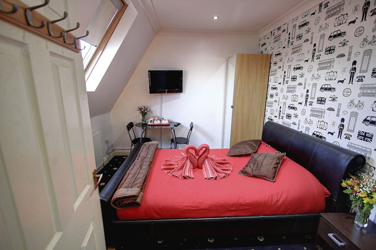 A bedroom with a red bedspread, a black headboard, and a wall with travel-themed decals.