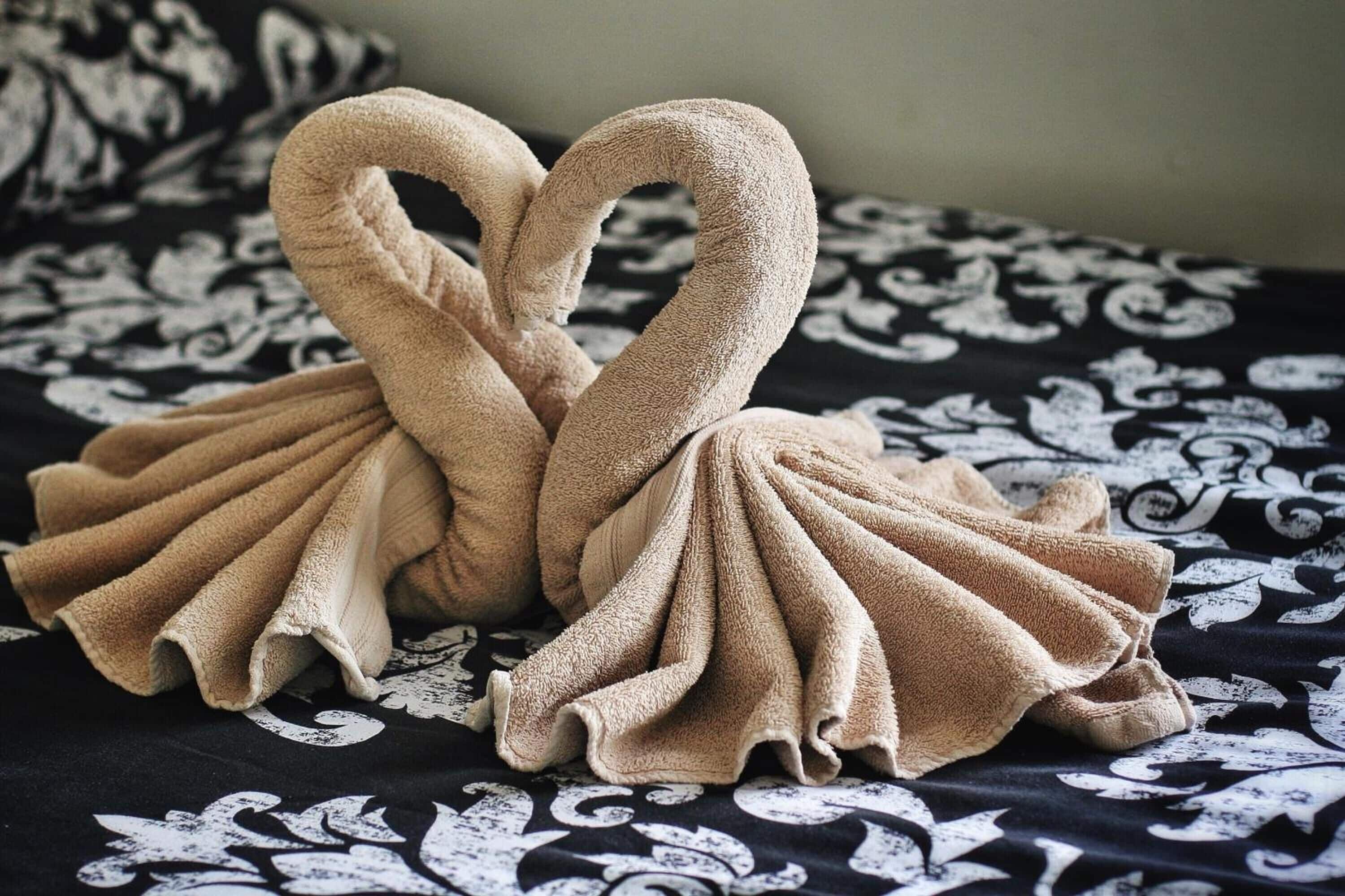 Una cama con un edredón estampado en blanco y negro y dos toallas con forma de cisne encima.